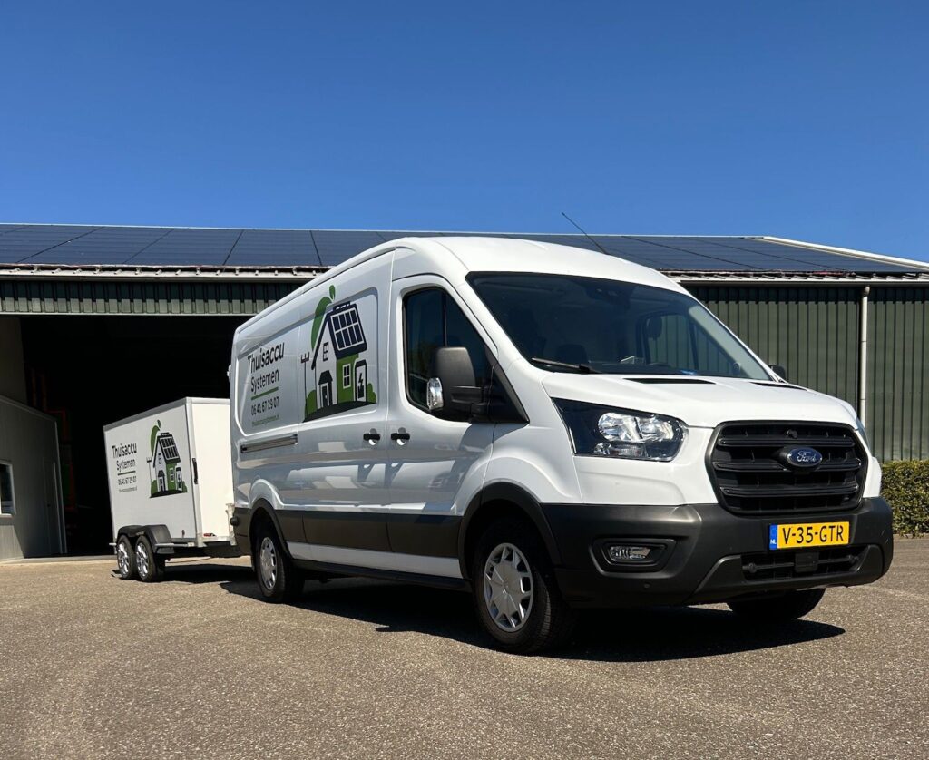 Bedrijfsbus met aanhanger van Thuisaccu Systemen bij een bedrijfspand met zonnepanelen