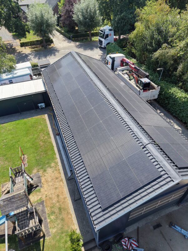 Schuin luchtbeeld van een schuurdak vol zonnepanelen tijdens de oplevering